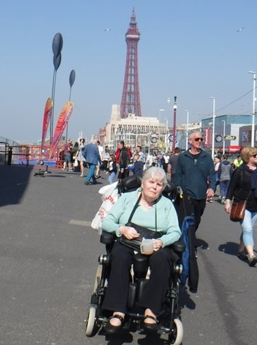 Lyn on promenade blackpool in her green jumper in her wheelchair