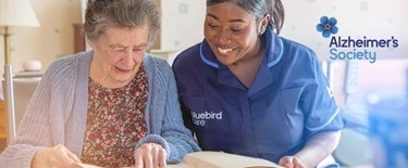 Elderly lady with Dementia reading with a carer