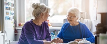 World Alzheimer’s Month: A family member and an an elderly chatting at the kitchen table with a book
