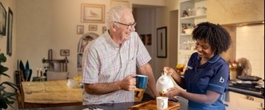 A carer making coffee for an elderly customer in the kitchen