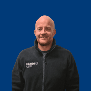 Image of Chris, our Registered Manager on a blue background
