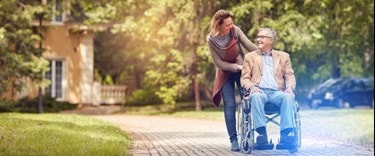 outside with a lady and a dementia patient in a wheel chair