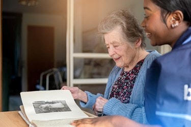 A Bluebird Care Care Expert chatting with a customer over a photo album
