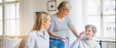 family at the kitchen table with elderly lady drinking water