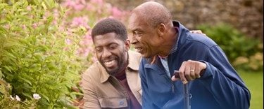 Carer in the garden with an elderly man using walking stick