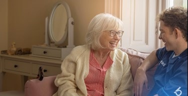 Female customer and male carer sitting on sofa laughing