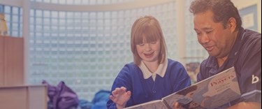Male carer reading a book with a child with educational needs