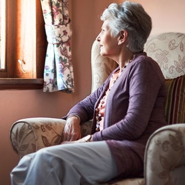 Elderly lady sitting on her own looking out the window