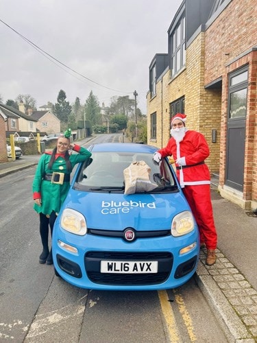 Julian and Sinead dressed as Santa and an elf delivering Christmas gifts