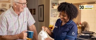 Carer and elderly puring tea