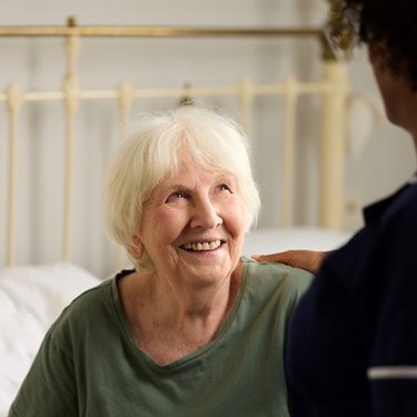 customer sat in bed looking up at care expert