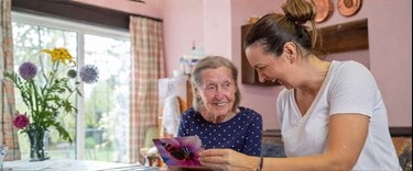 Elderly lady reading a card with a carer at home