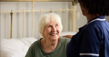 customer sat in bed looking up at care expert