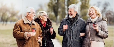 Elderly couples walking together each with a cup of coffee
