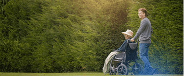 A lady in a wheelchair outside with a carer