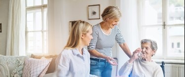 family at the kitchen table with elderly lady drinking water
