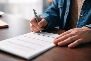 Image of man signing document on a wooden table