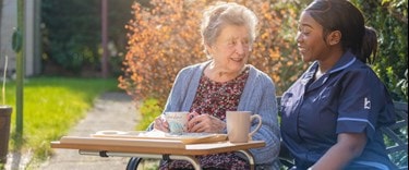 Carer outside have a chat and tea with a elderly lady