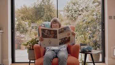 Customer sitting in their own home reading the paper
