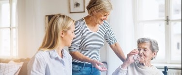 family at the kitchen table with elderly lady drinking water