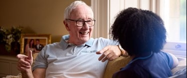 an elderly man and a live-in carer chatting at home