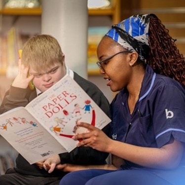 Carer reading to a disabled little boy