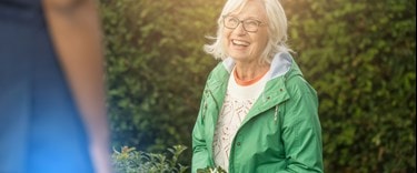 elderly Lady in the garden smiling at a carer