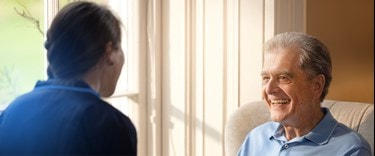 Elderly man chatting to a carer in the lounge