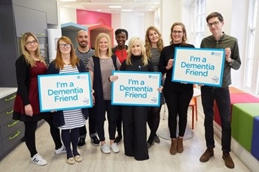 A photo of the team holding a banner which says "I'm a Dementia friend"