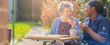 Outdoors having a warm drink and a bite to eat with elderly lady and her carer