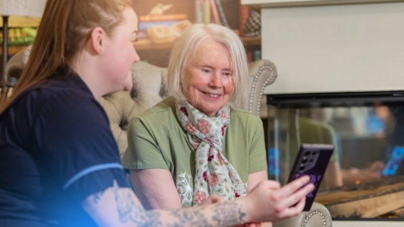 Carer showing a mobile image to an elderly customer