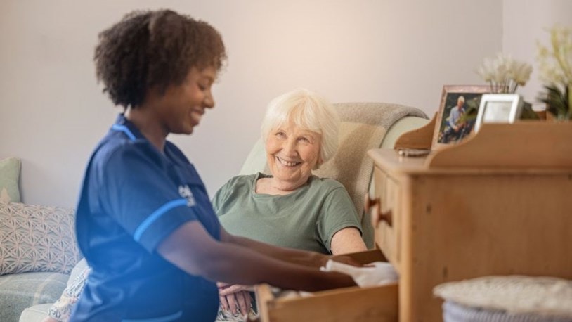 carer packing clothes in a drawer for an elderly patient