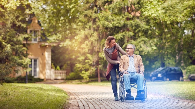 A lady assisting an elderly in a wheelchair