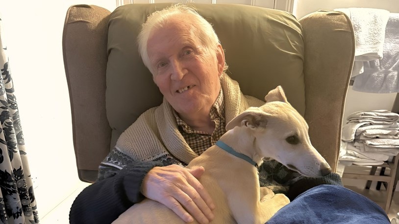 elderly man cuddling his pet dog at home
