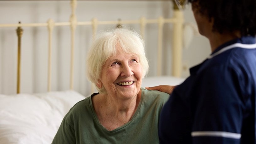 customer sat in bed looking up at care expert