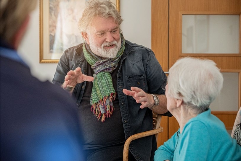 Si King talking to Bluebird Care carers and customers wearing a green scarf talking passionately